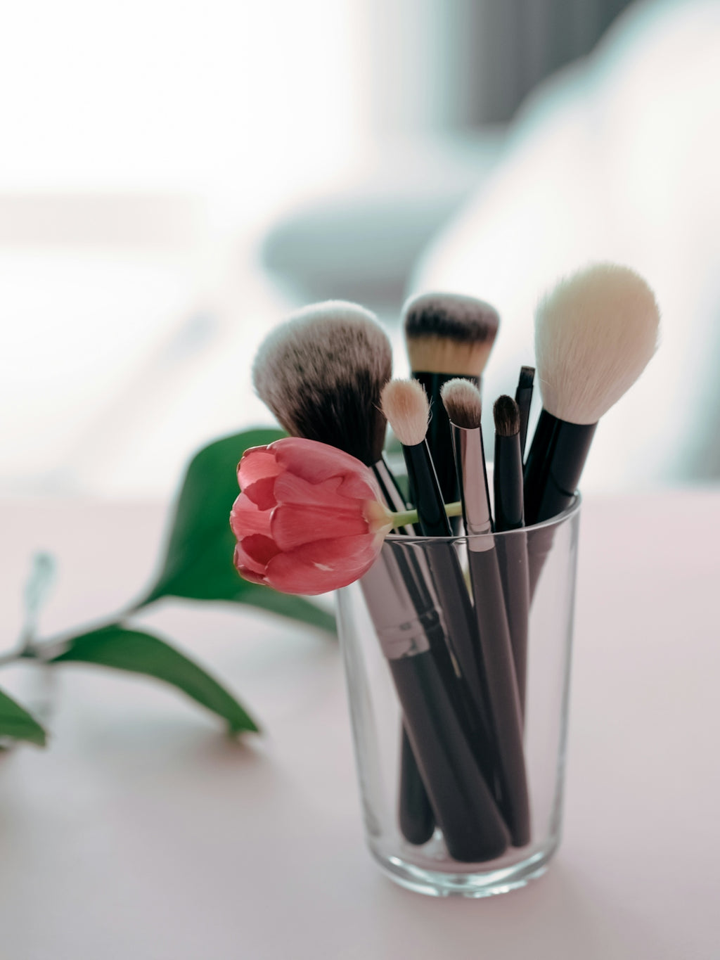 a glass filled with makeup brushes on top of a table