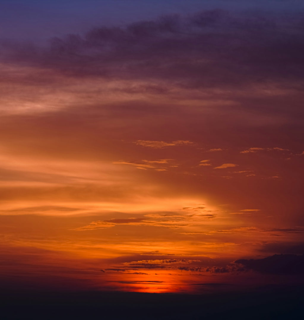 A plane flying in the sky at sunset