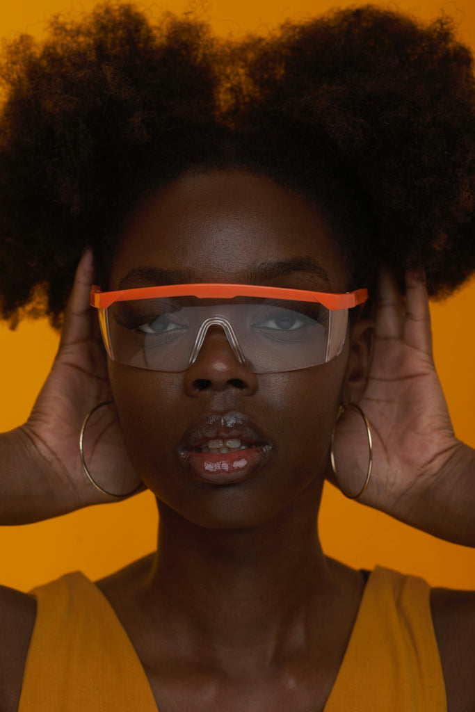 Woman models safety glasses with an expressive look.
