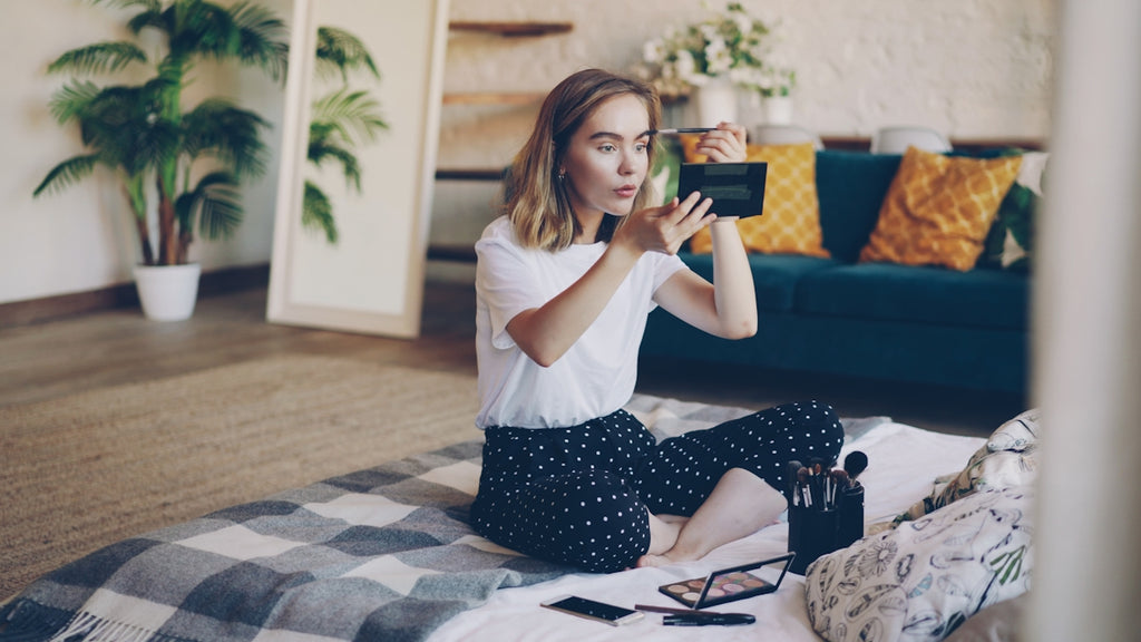 Young woman applying makeup on floor