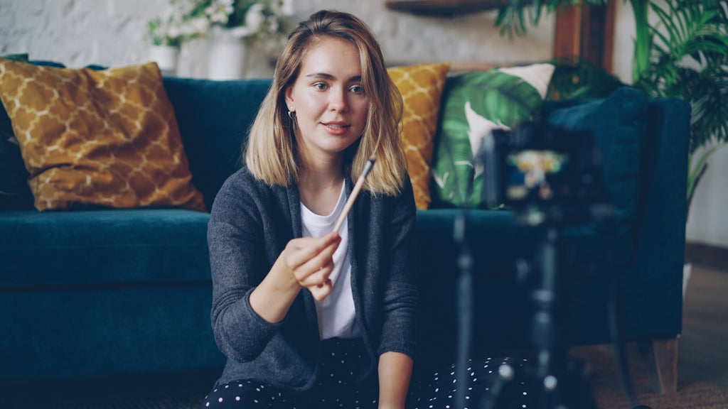 Woman holding makeup brush in front of camera