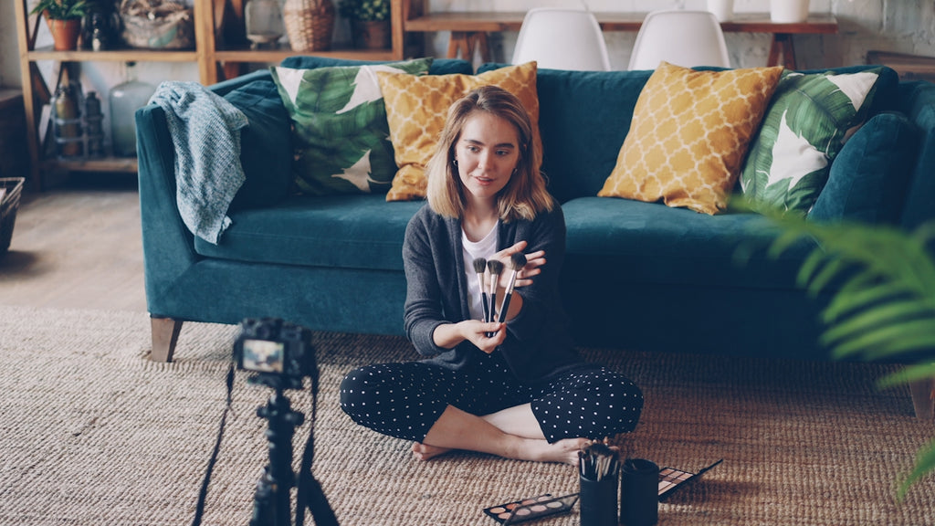 Woman filming herself with a camera in a living room.