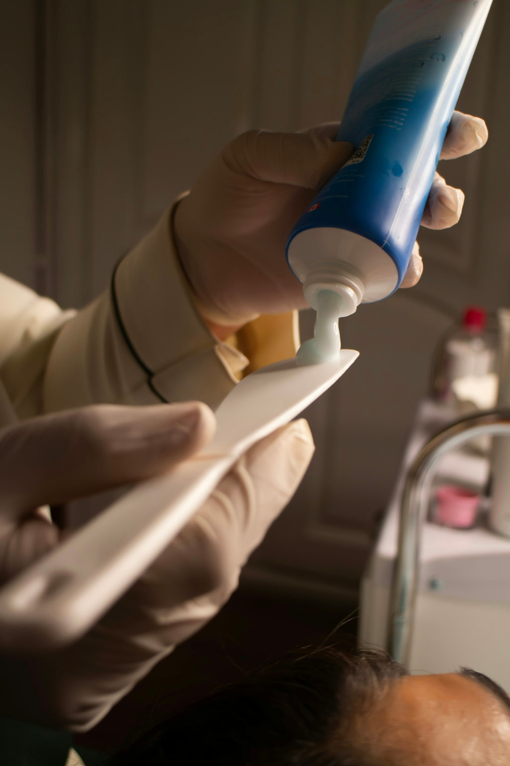 Dentist applying paste to dental tool.