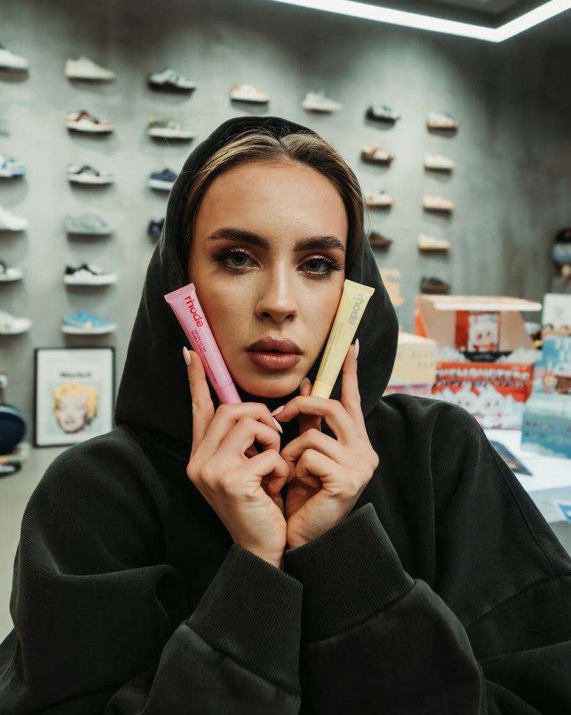 Woman in hoodie holds pink and yellow tubes