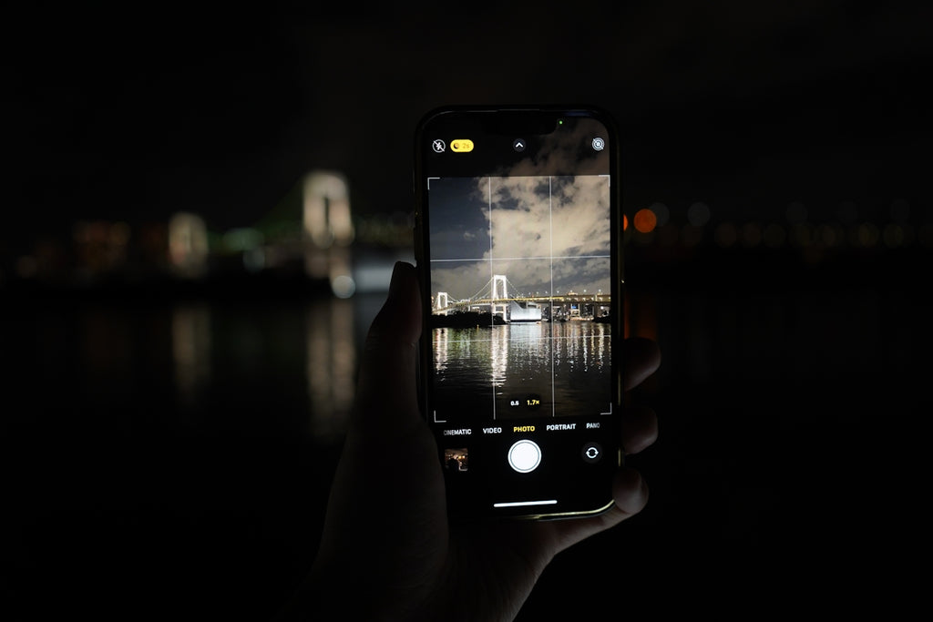 Hand holding smartphone capturing city lights at night