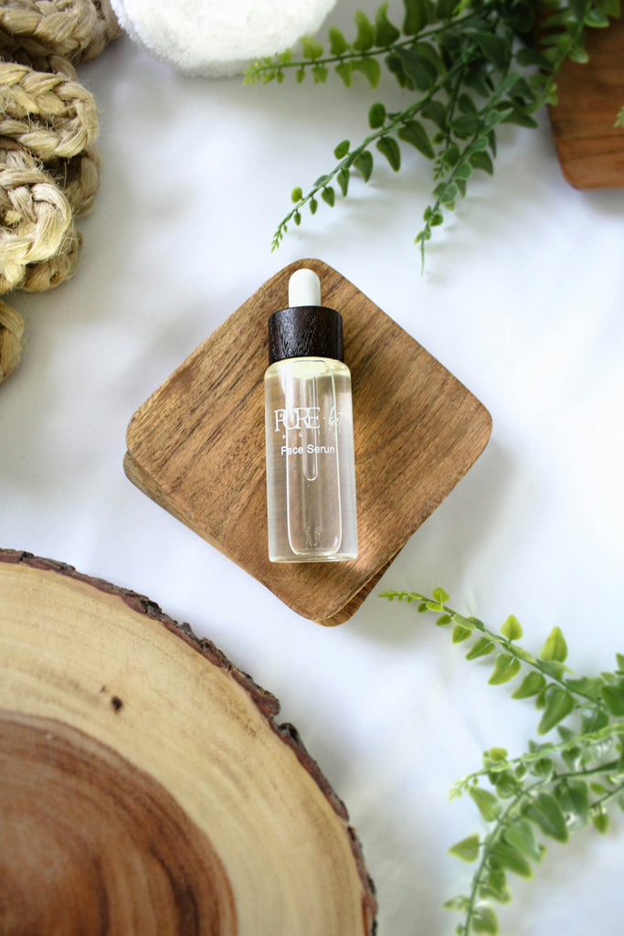 Clear serum bottle on a wooden coaster with greenery